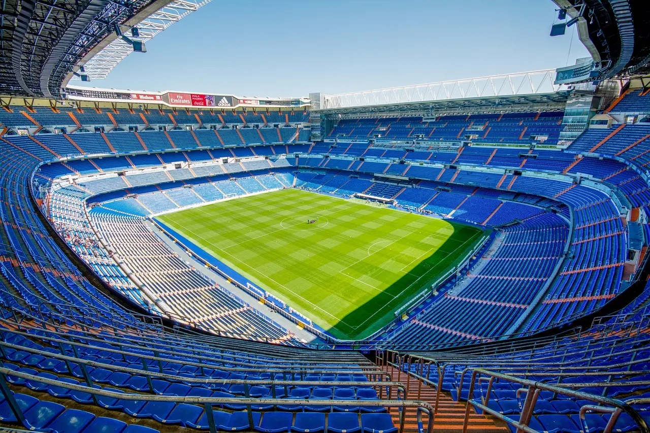 Fodboldstadion med grøn bane og blå tribuner